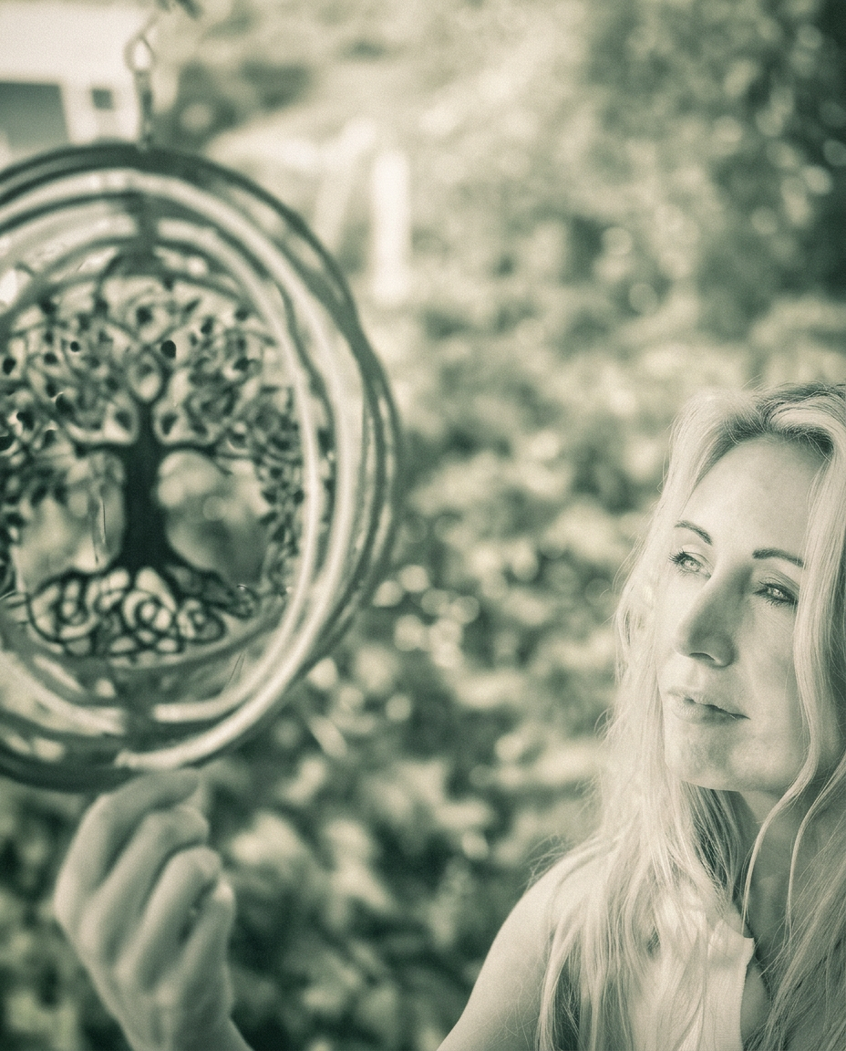 Anne Marie Sweeny holding a tree of life ornament in a sunlit garden